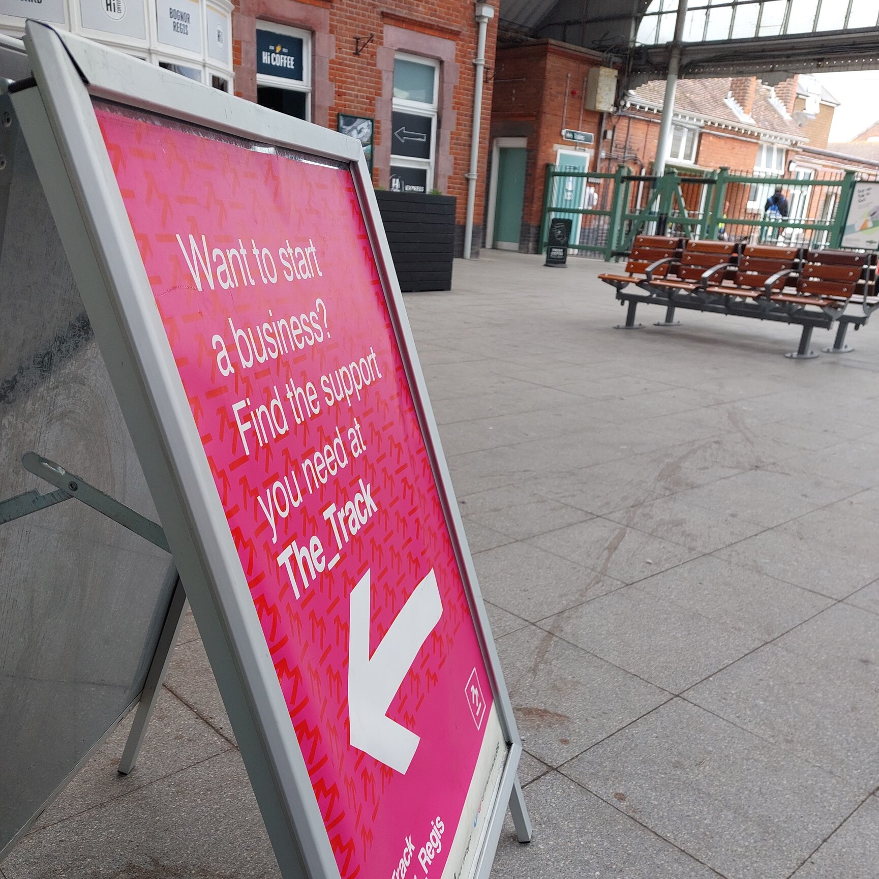 The_Track's bright pink A-frame sign which is standing in Bognor Regis Train Station. The frame reads "Want to start a business? Find the support you need at The_Track"
